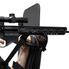 Close-up of a rifle with a scope resting on a support bracket that is mounted to a bulletproof shield