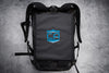 Lifestyle image of caliberx-iiia soft body armor rectangle laying on top of compatible backpack on a grey background